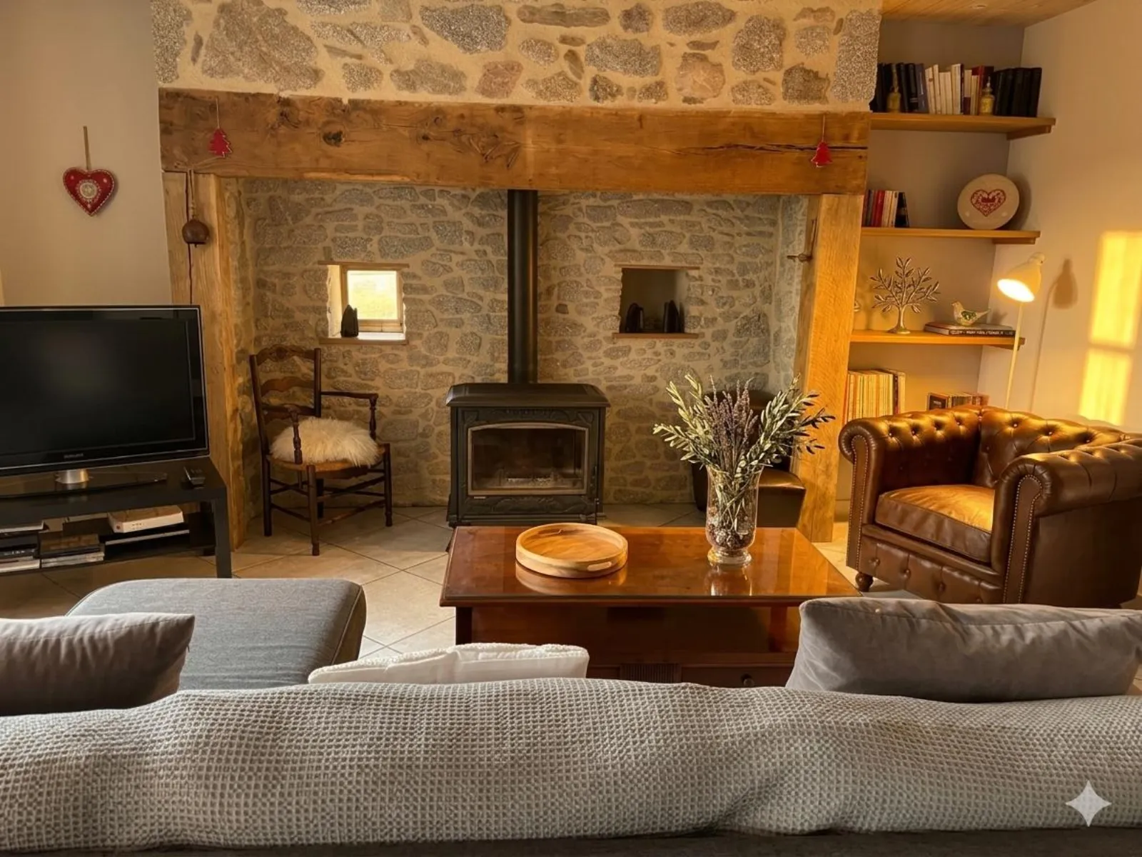 Cantou in pietra con stufa a legna nel soggiorno del Gîte Angèle, Cantal