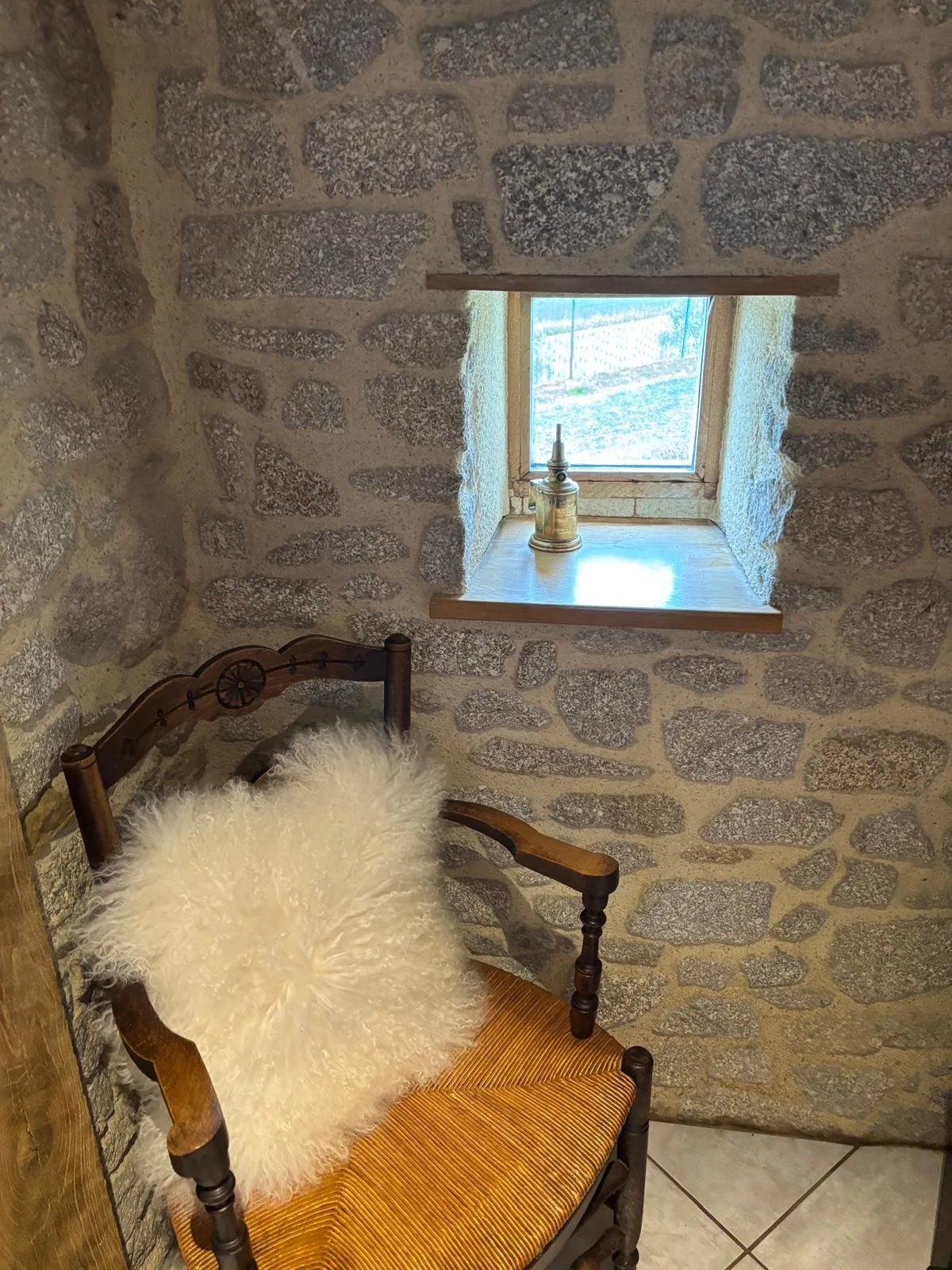 Angolo relax in pietra con poltrona antica e pelle di pecora