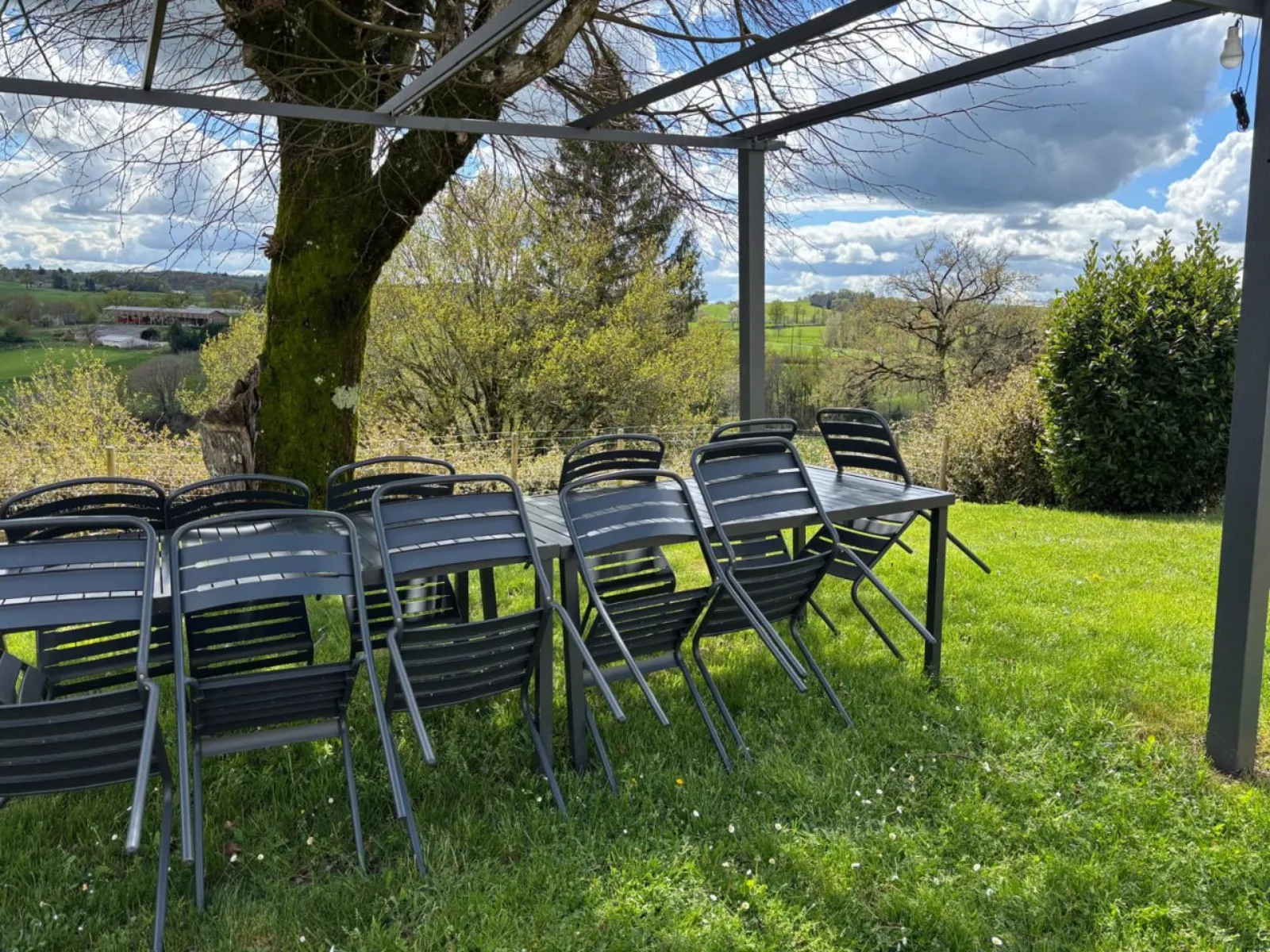 Pergolato con grande tavolo esterno e vista campagna al Gîte Angèle